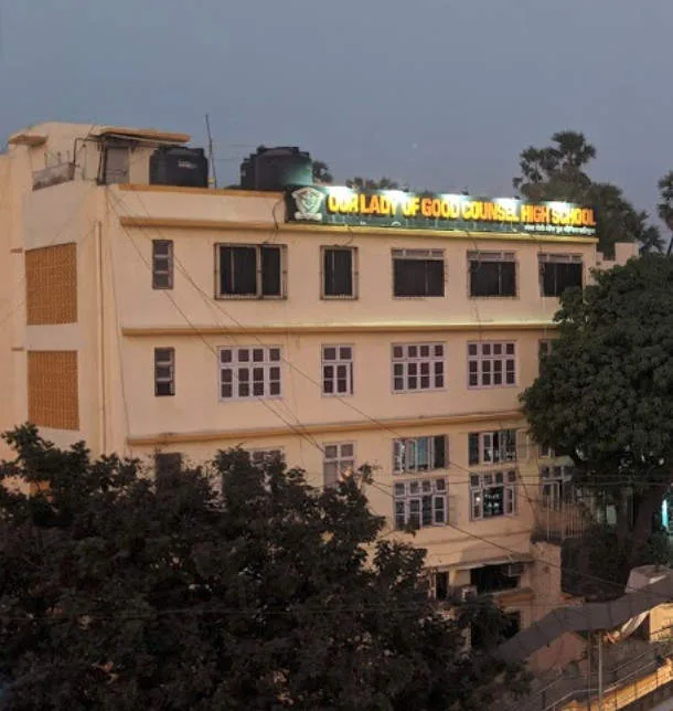 The school building at dusk, with its rooftop sign lit